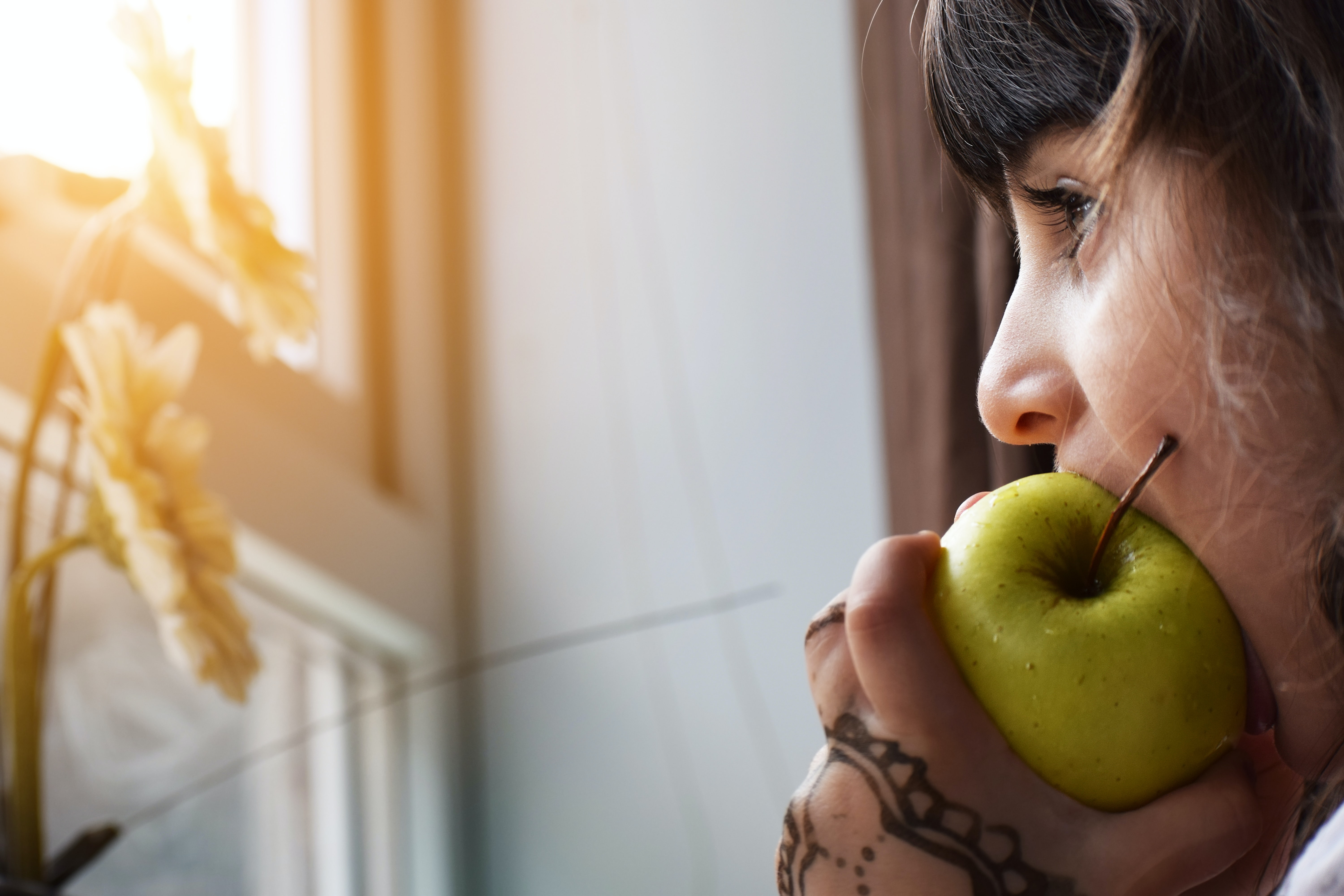 Little girl eating an apple looking out the window